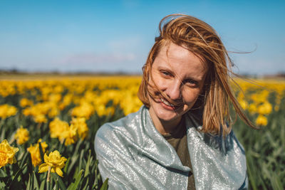 Portrait of woman with yellow flowers in field