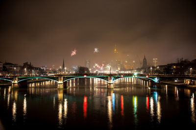 Illuminated bridge over river against sky at night