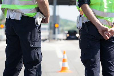 Midsection of man holding umbrella while standing on road