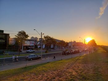 Road by city against sky during sunset