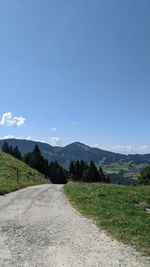 Road amidst green landscape against sky