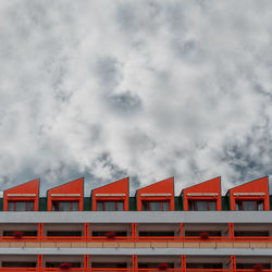 Low angle view of red building against cloudy sky