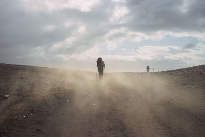 Rear view of person walking on land against sky