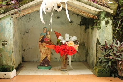 Close-up of virgin mary and jesus christ by flower vase in niche