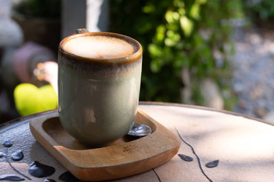 Cup of coffee latte in green poetry mug on old wooden background in the morning sunlight