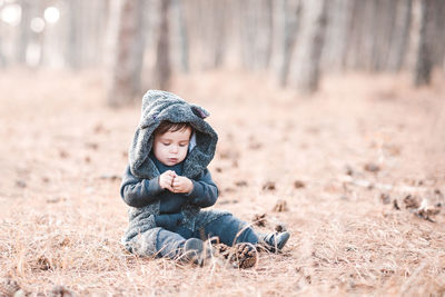 Cute boy sitting on grass in forest