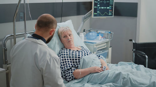 Rear view of doctor examining patient in hospital