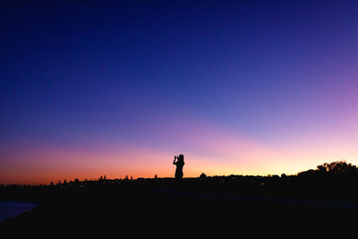 Silhouette people standing on land against sky during sunset