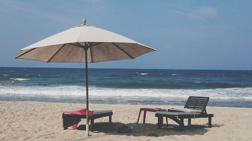 Deck chairs on calm beach against clear blue sky