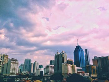 Skyscrapers in city against cloudy sky