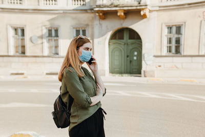 Woman standing on mobile phone in city