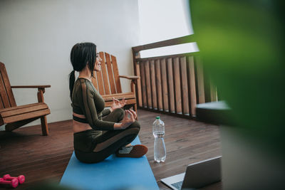 Rear view of woman using phone while sitting on table