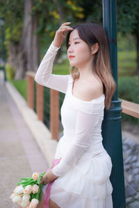 Portrait of young woman standing against trees