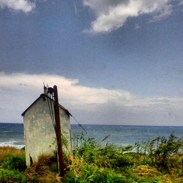 sea, sky, horizon over water, water, tranquil scene, tranquility, beach, cloud - sky, scenics, grass, nature, cloud, beauty in nature, shore, cloudy, built structure, day, idyllic, remote, non-urban scene