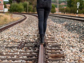 Low section of woman standing on railroad track