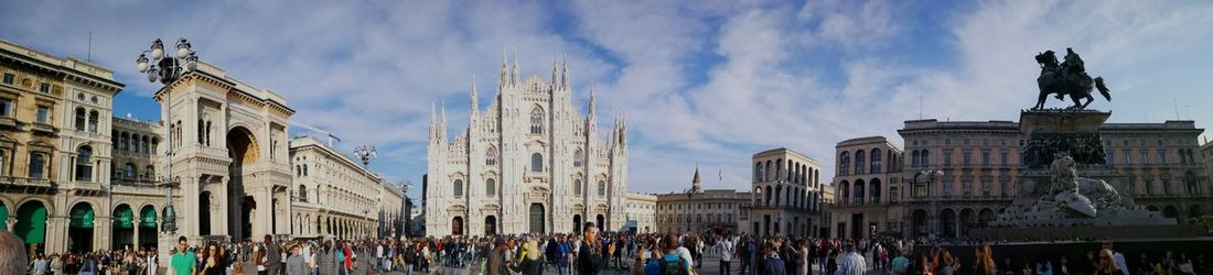 Panoramic view of crowd in city against cloudy sky