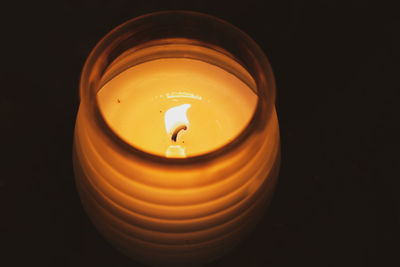 Close-up of lit candle against black background