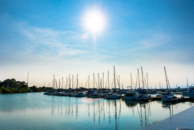 Sailboats moored on harbor against sky