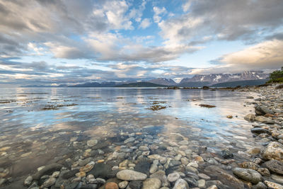 Idyllic shot of lake and lyngen alps against cloudy sky