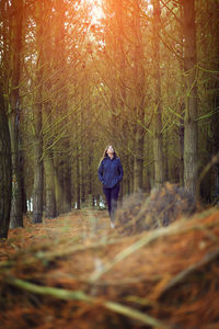 Woman looking up while walking in forest during winter