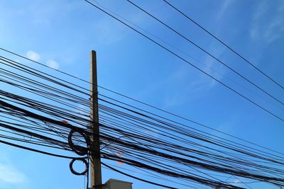 Low angle view of electricity pylon against blue sky