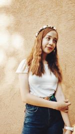 Portrait of young woman standing against wall