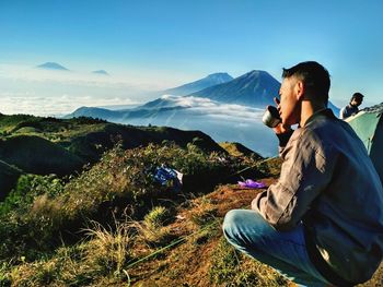 People sitting on mountain against sky