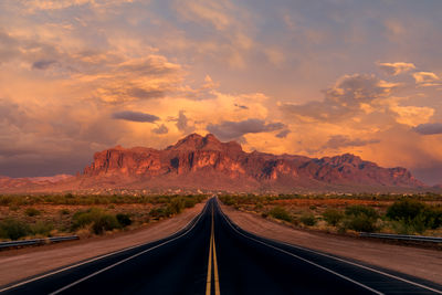 Long, straight road leading to the superstition mountains at sunset