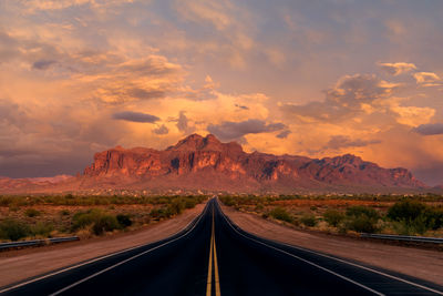 Long, straight road leading to the superstition mountains at sunset