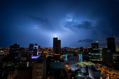 Lightning over illuminated buildings in city at night