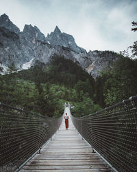 Rear view of woman on footbridge against mountains
