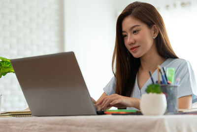 Young woman using phone on table