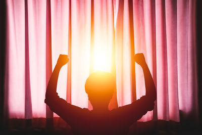 Silhouette woman standing by window during sunset