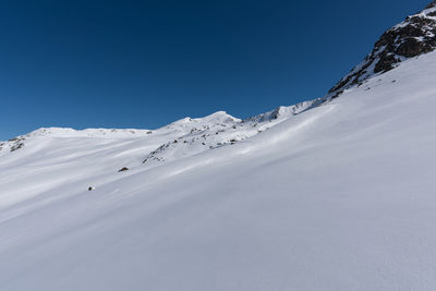 Scenic view of snowcapped mountains against clear blue sky