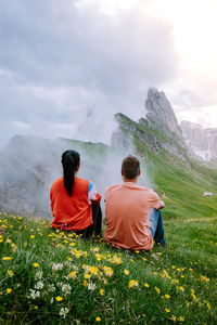 Rear view of people looking at mountains against sky