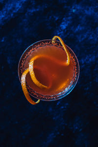 Top down shot of orange cocktail on blue velvety background