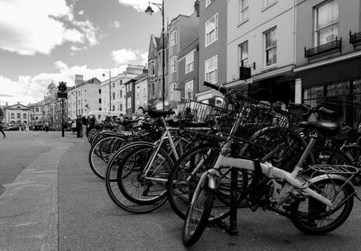 Bicycles parked on street in city against sky