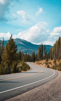 Road by trees and mountains against sky