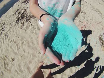 High angle view of girl holding powdered paint while standing at beach