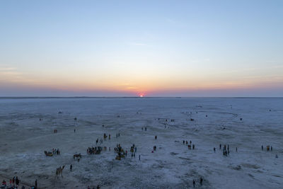 High angle view of people on beach against sky during sunset