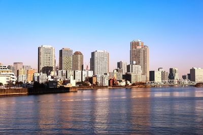 Riverbank of sumida city river in sunny morning tokyo with skyscrapers and water reflections