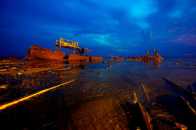 Aerial view of illuminated ship in water against sky