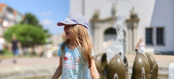 Midsection of woman wearing hat standing in city