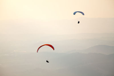 People paragliding against sky during sunset