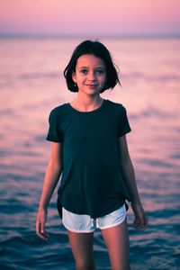 Portrait of woman standing against sea during sunset