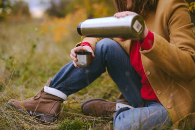 Low section of woman pouring drink in bottle cap