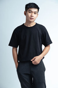 Portrait of young man standing against white background