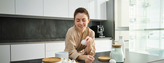 Portrait of young woman standing in kitchen