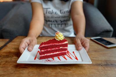 Midsection of woman holding ice cream on table