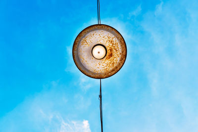 Low angle view of pendant light hanging against blue sky